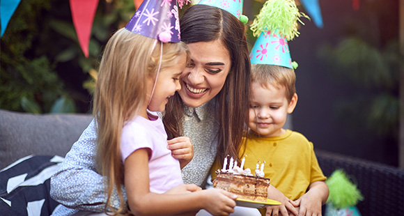 a mother celebrating a birthday with two of her children at a chlidren's birthday party